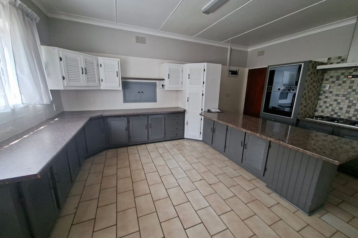 Spacious kitchen featuring extensive built-in cabinetry, laminate countertops, tiled flooring, and integrated appliances including an oven and hob.