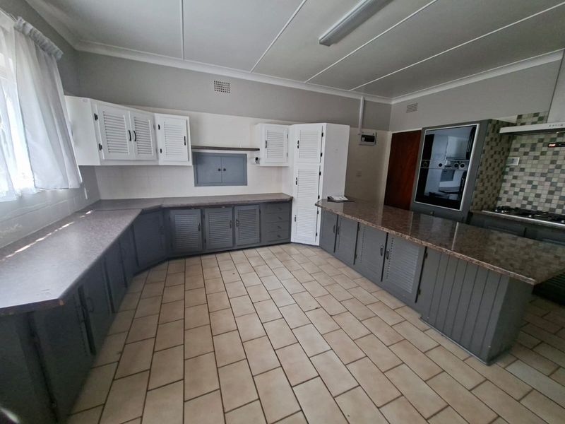 Spacious kitchen featuring extensive built-in cabinetry, laminate countertops, tiled flooring, and integrated appliances including an oven and hob.