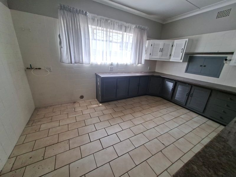 A functional scullery or utility area featuring built-in cabinetry, laminate countertops, and tiled flooring, offering a practical space for laundry or additional kitchen prep.