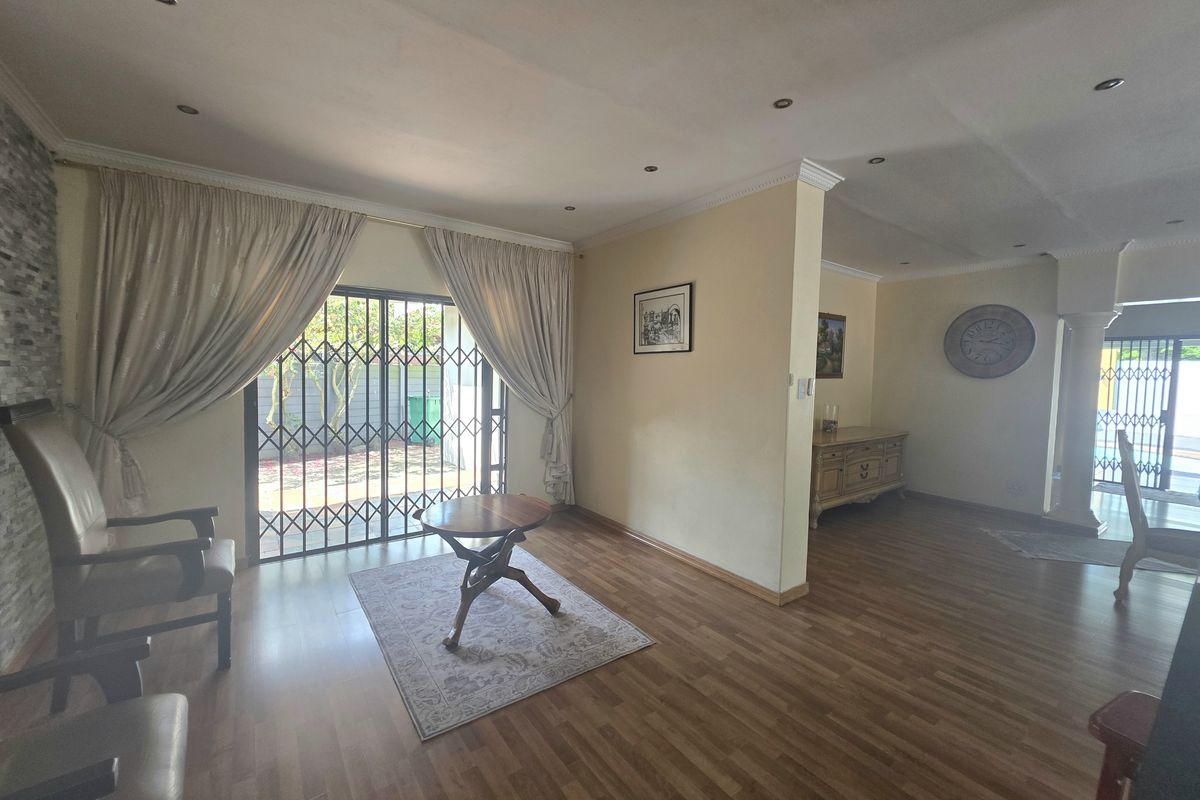 Spacious living area featuring laminate flooring, recessed downlights, and a stone feature wall, with direct access to the outdoor area via sliding glass doors.