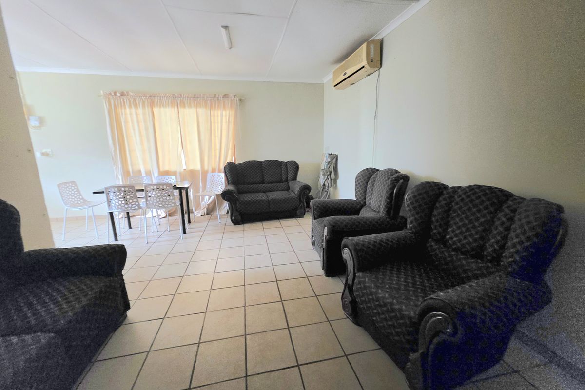 Spacious living area featuring tiled flooring, a wall-mounted air conditioning unit, and a drop ceiling, offering a functional layout for family living.