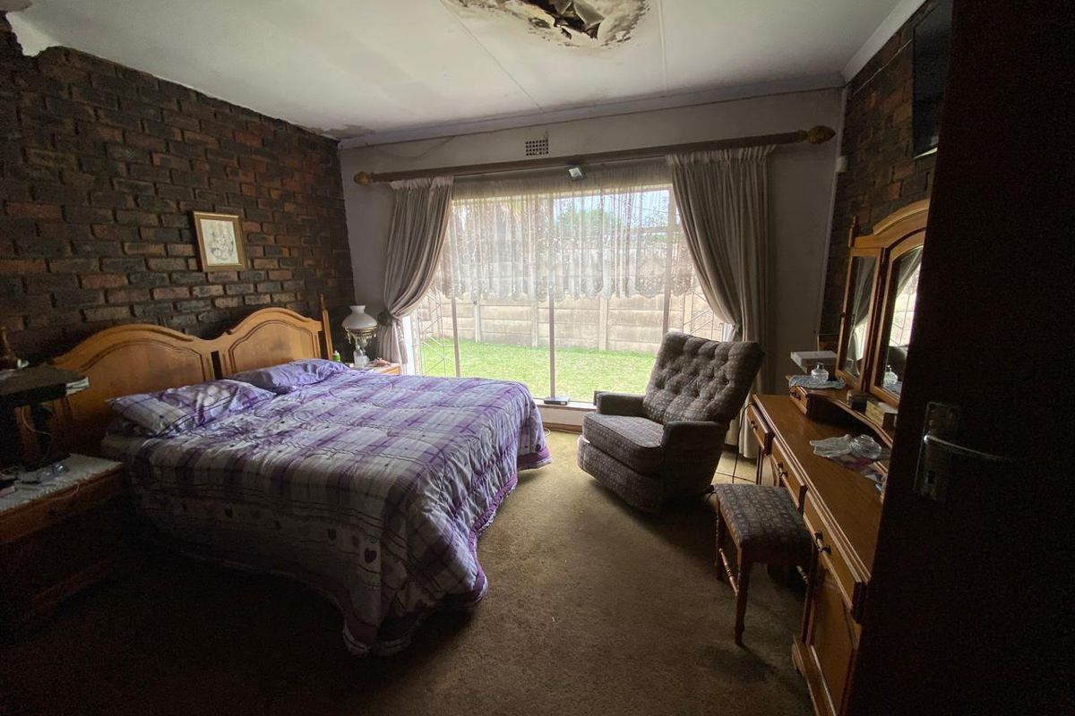 A bedroom featuring exposed brick walls, large sliding glass doors, and significant ceiling water damage requiring repair.