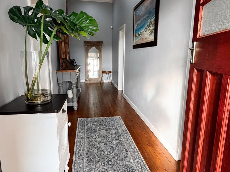 A well-maintained hallway featuring polished timber flooring, a classic panelled ceiling, and a solid timber entrance door.