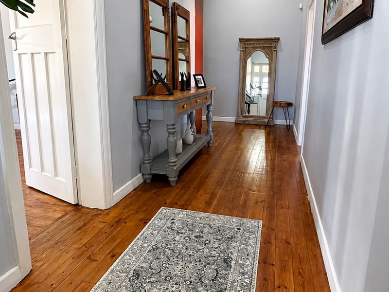 A bright and welcoming hallway featuring polished hardwood flooring, a decorative coffered ceiling, and neutral wall finishes.