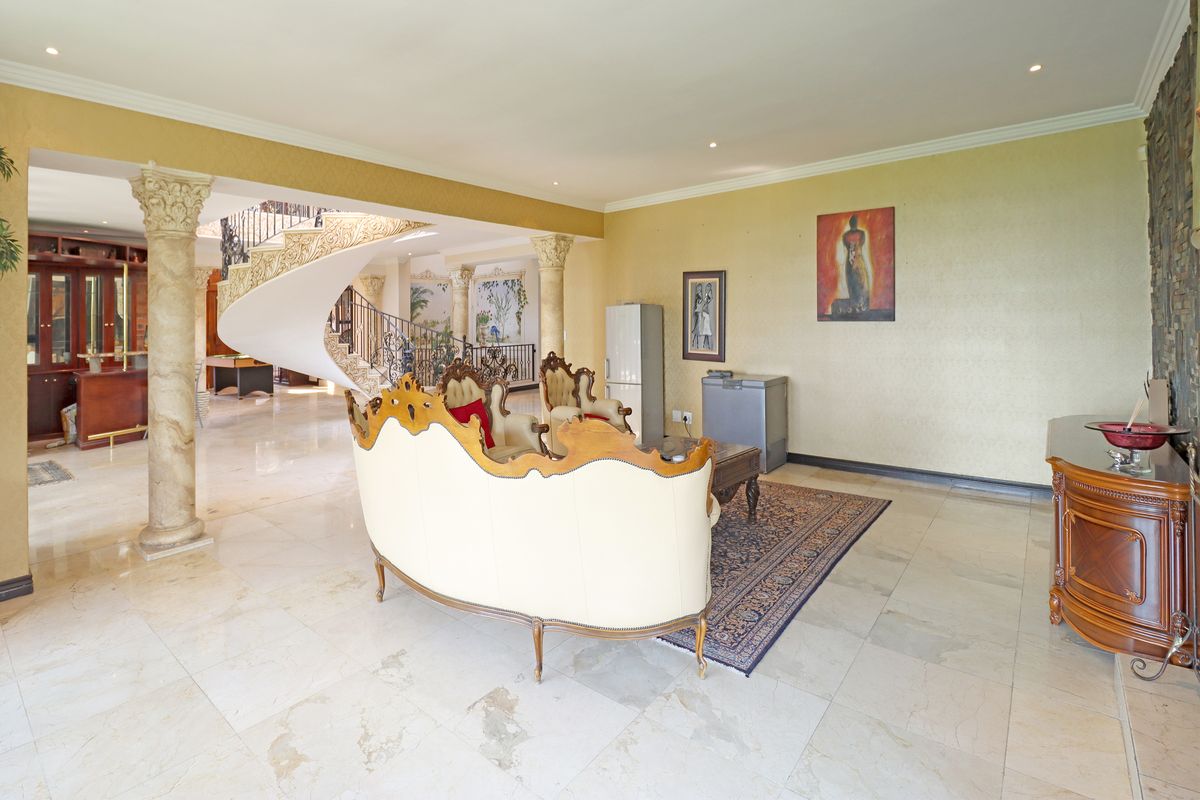 Spacious living area featuring elegant marble flooring, decorative stone columns, and a grand spiral staircase leading to the upper level.