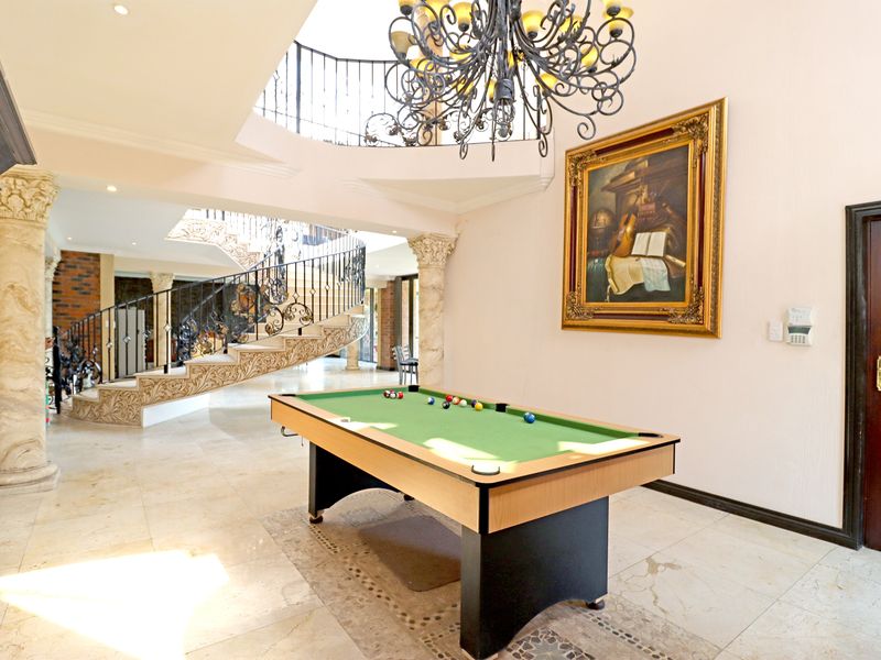 Spacious living area featuring a grand spiral staircase with wrought iron balustrade, decorative stone columns, and elegant stone flooring.