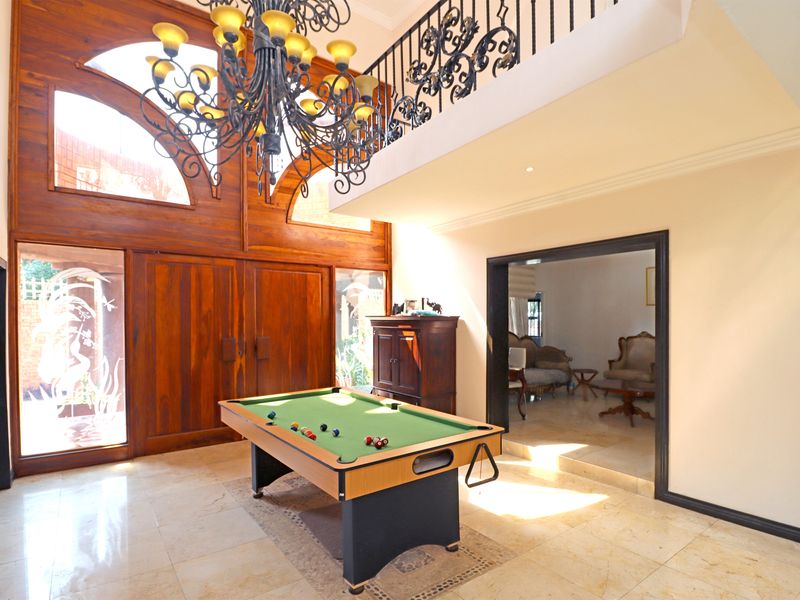 Spacious living area featuring double-height timber-framed windows, stone tile flooring, and an elegant wrought iron mezzanine balustrade overlooking the room.