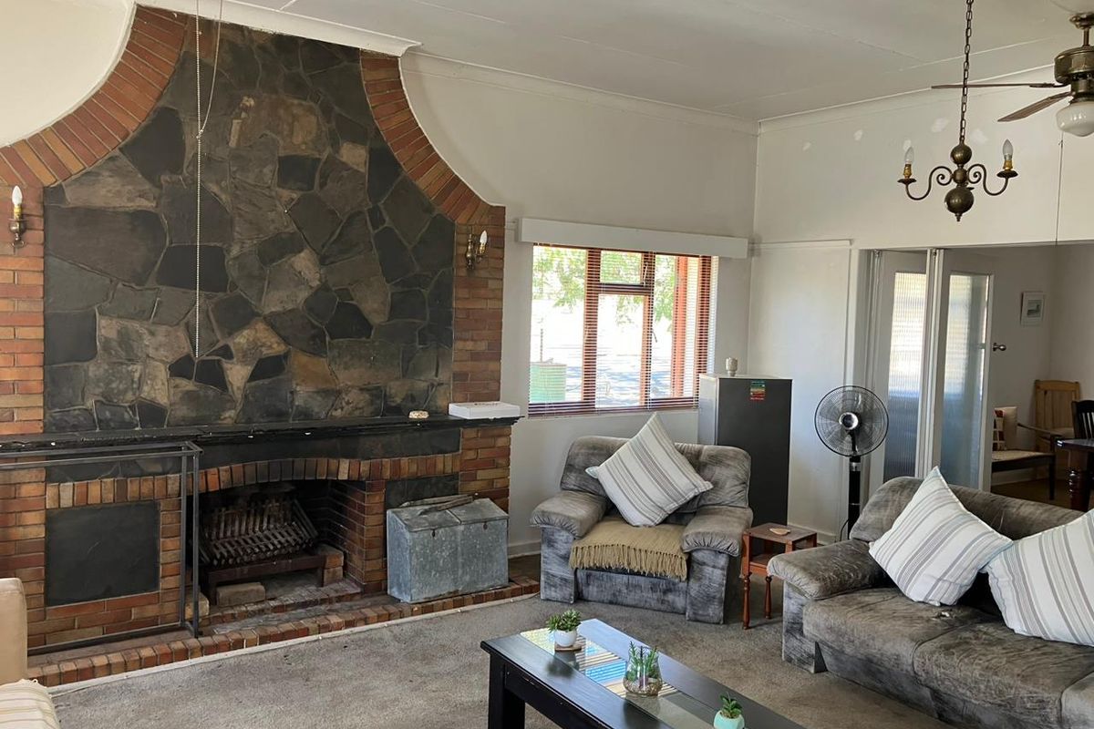 Spacious living room featuring a prominent stone and brick fireplace, neutral walls, and large windows, offering a comfortable and traditional farm-style living space.