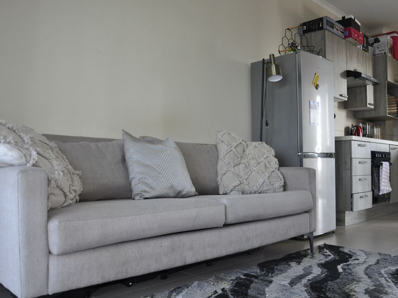 An open-plan living area featuring a modern kitchen with built-in cabinetry, oven, and extractor fan, seamlessly connected to the living space.