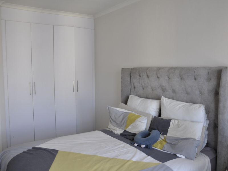 A well-maintained bedroom featuring neutral walls, coving, and ample built-in cupboard storage.