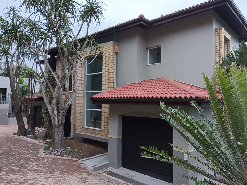 Front elevation of a modern two-story house featuring a tiled roof, brick accents, a garage, and a paved driveway.