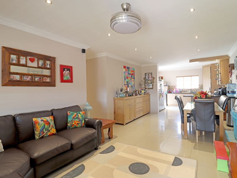 An open-plan living and dining area featuring tiled flooring, recessed lighting, and a functional kitchen with built-in cabinetry and an island.