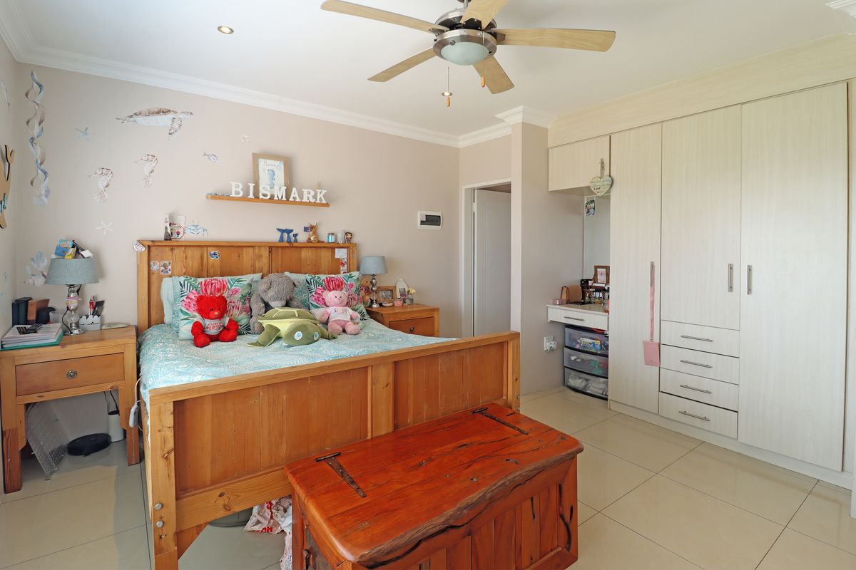 A well-maintained bedroom featuring built-in cupboards, tiled flooring, and a ceiling fan, offering a functional and comfortable living space.