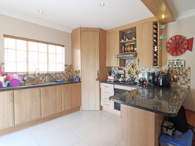 A functional kitchen featuring light wood cabinetry, granite countertops, a built-in oven with gas hob, and a tiled backsplash.