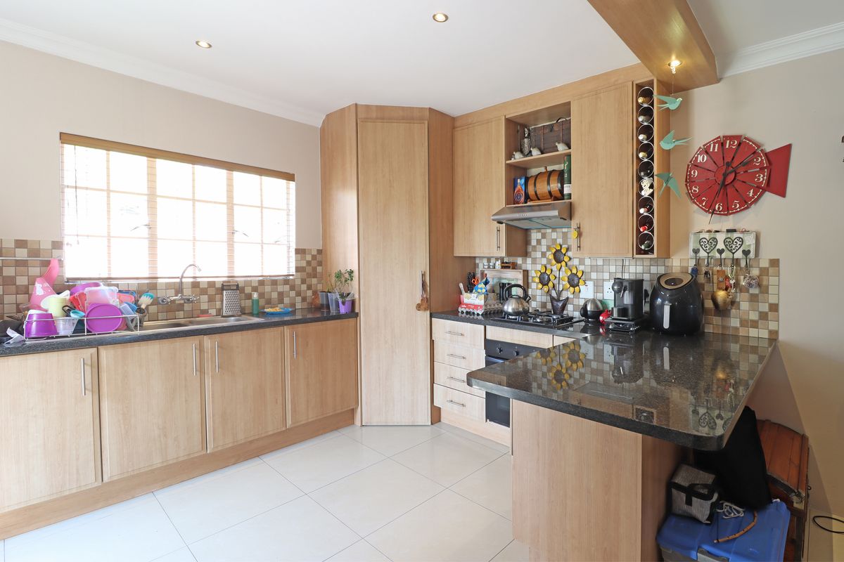 A functional kitchen featuring light wood cabinetry, granite countertops, a built-in oven with gas hob, and a tiled backsplash.