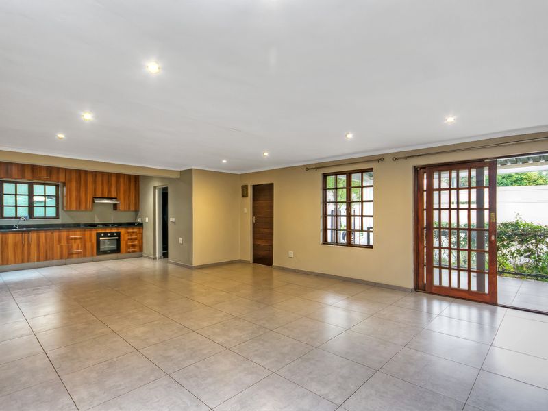 Spacious open-plan living area featuring tiled floors, recessed lighting, and a modern kitchen with built-in cabinetry, granite countertops, and integrated appliances.