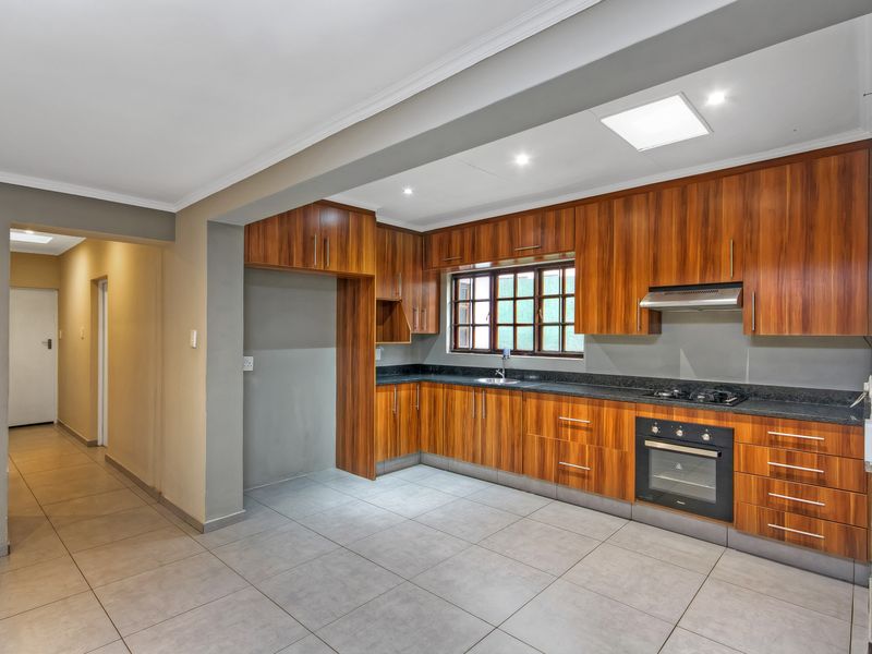 A modern, well-maintained kitchen featuring warm wood-toned cabinetry, granite countertops, integrated appliances, and neutral tiled flooring, offering a clean and functional workspace.