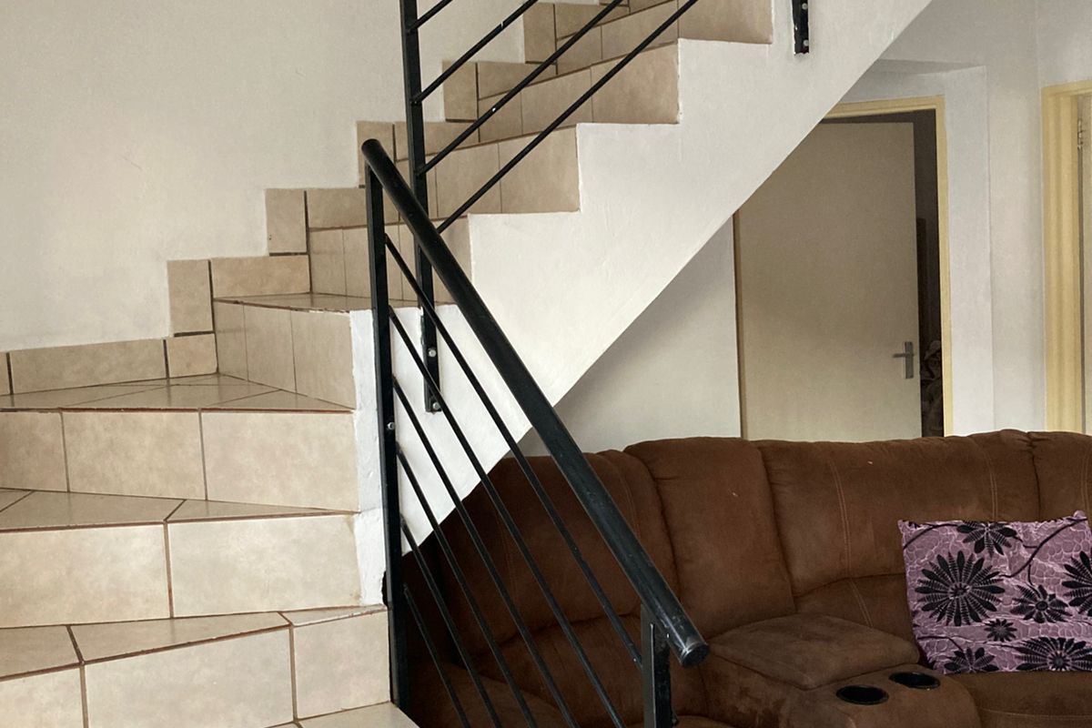 Living area featuring a tiled staircase with a black metal balustrade, providing access to the upper level of the townhouse.