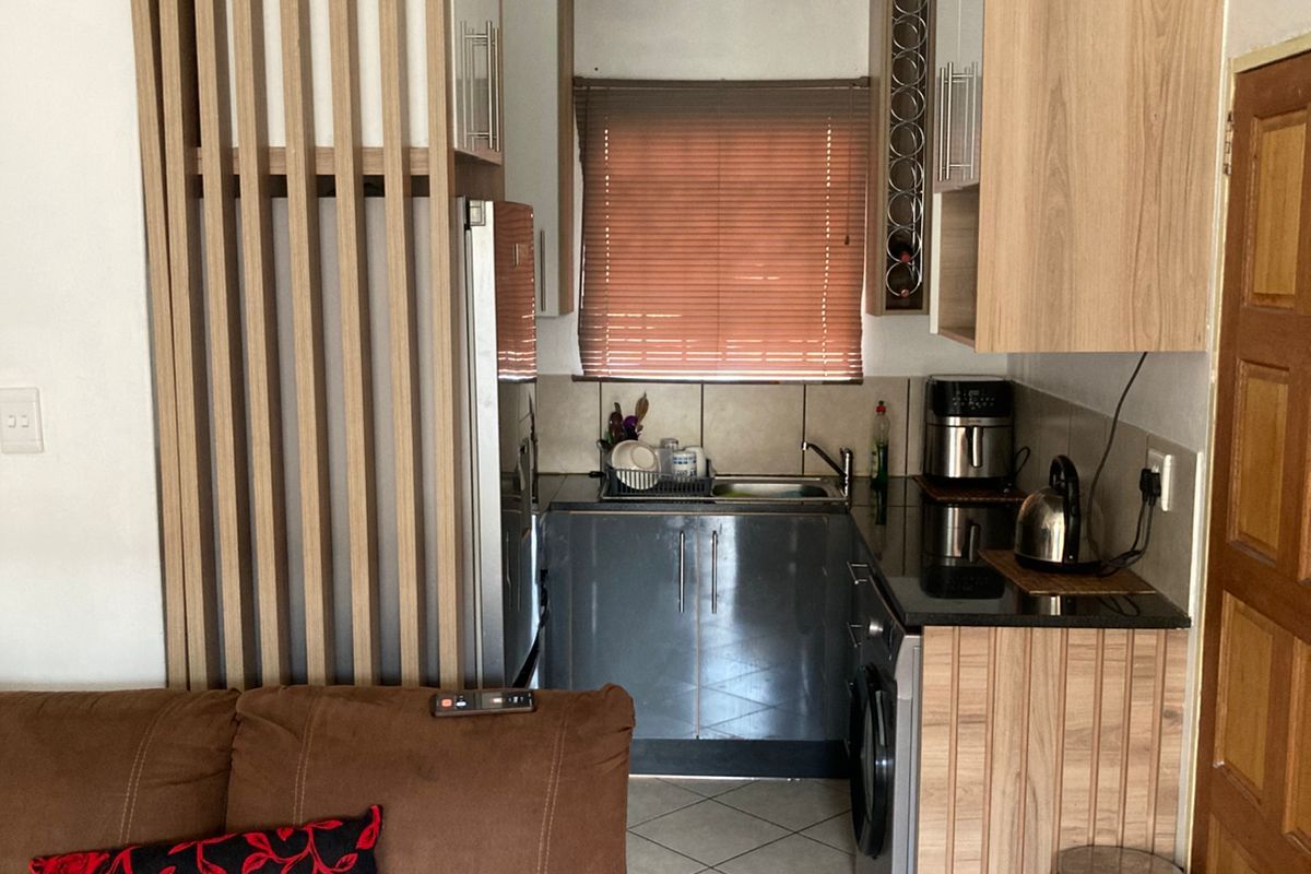Compact kitchen featuring modern wood-look cabinetry, granite countertops, tiled flooring, and integrated storage solutions, providing a functional and efficient workspace.