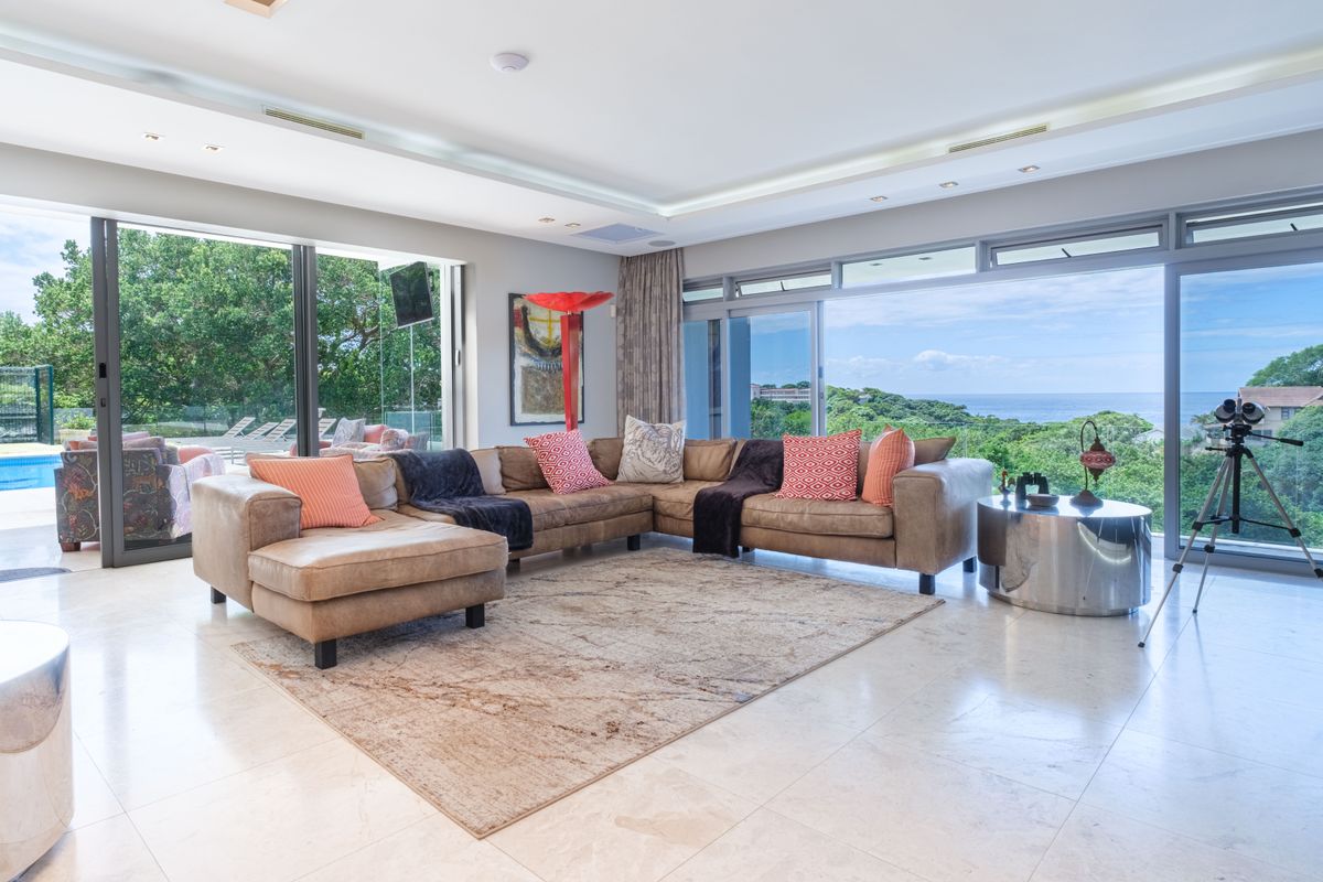 Spacious living room featuring large sliding glass doors, polished stone flooring, and recessed ceiling lighting with expansive coastal views.