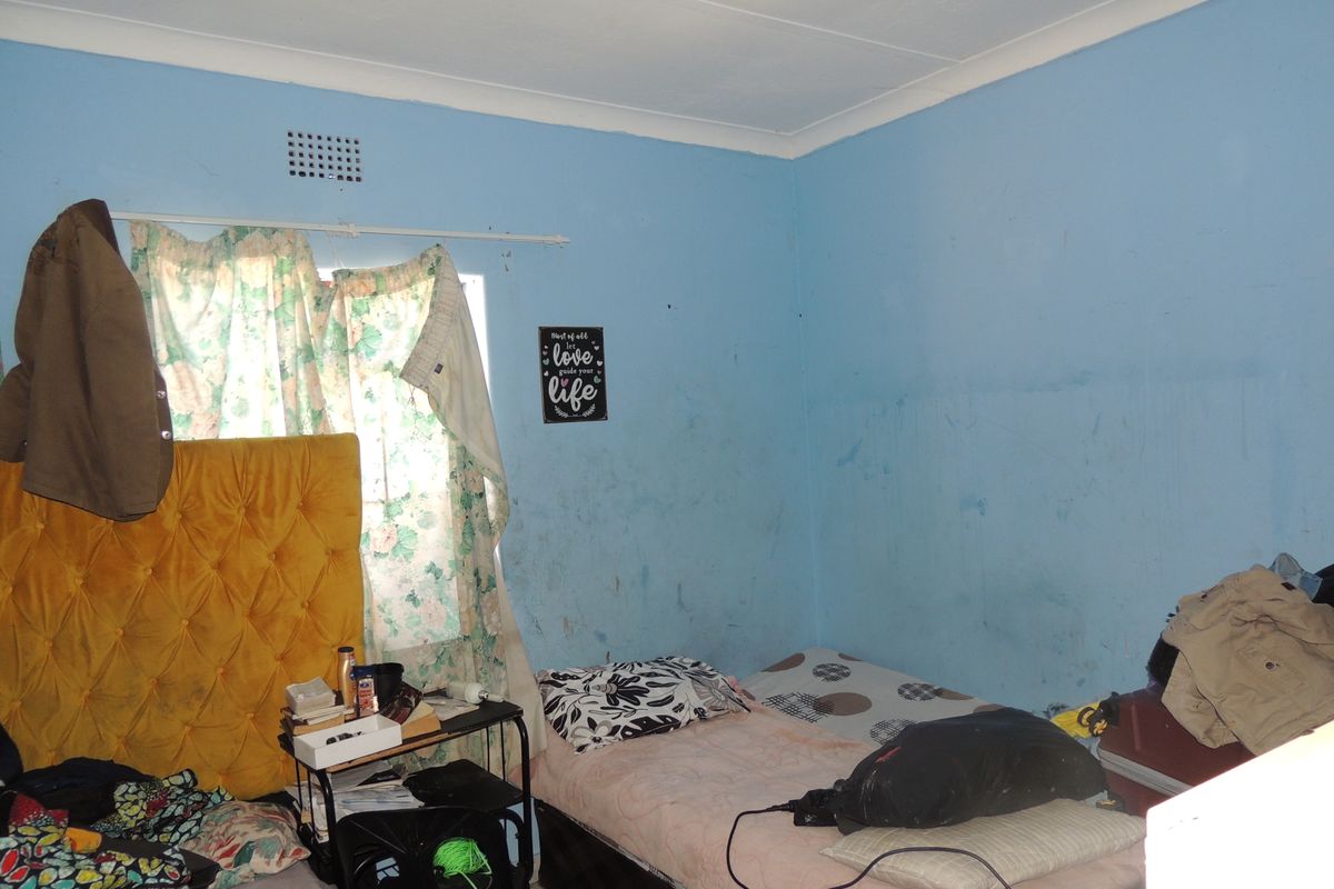 A bedroom featuring blue walls with visible surface wear and staining, requiring cosmetic updates and fresh paint to improve the overall condition.