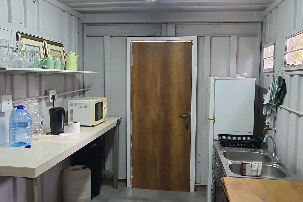 A functional utility kitchen space featuring a double stainless steel sink, laminate countertop, and industrial-style corrugated metal wall construction.