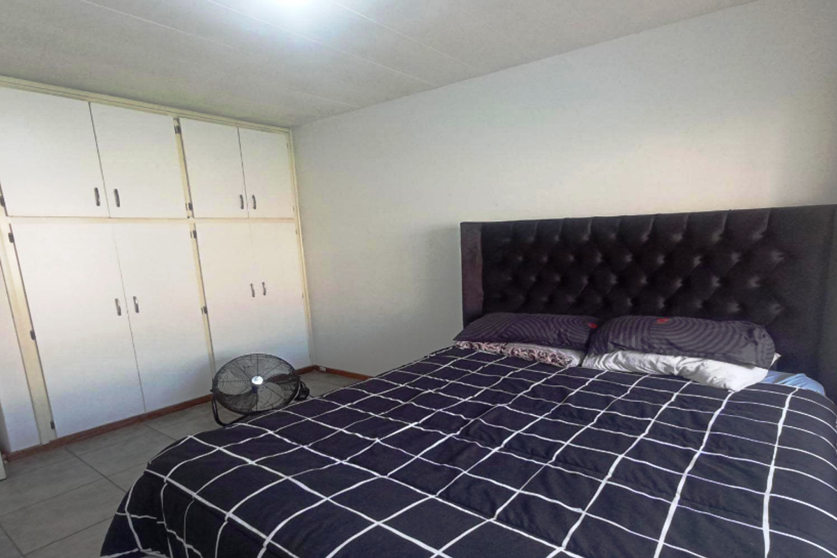 A bedroom featuring built-in floor-to-ceiling cabinetry and tiled flooring, offering functional storage space.