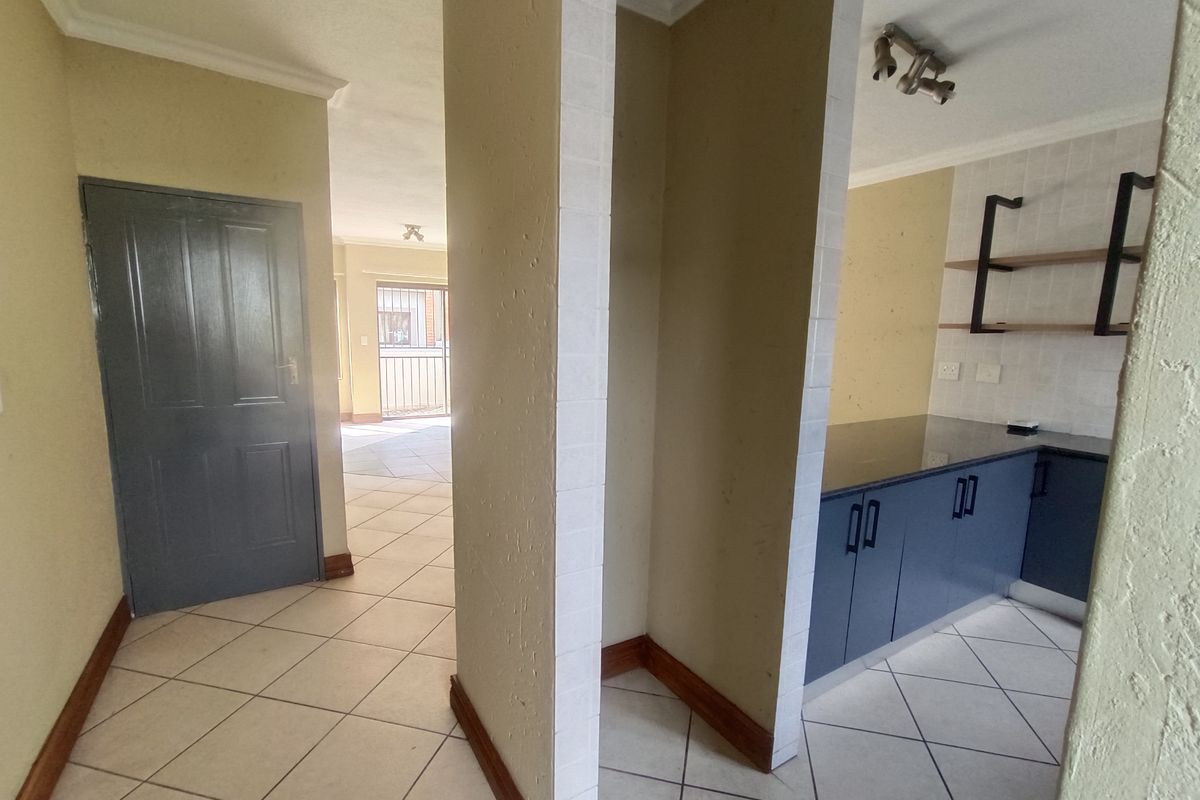 A functional kitchen area featuring dark blue cabinetry, granite countertops, and tiled flooring, with an open-plan layout leading to the living space.