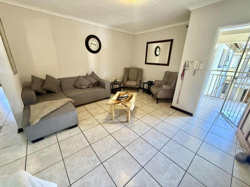 A well-lit living room featuring neutral tiled flooring and direct access to an outdoor balcony area.