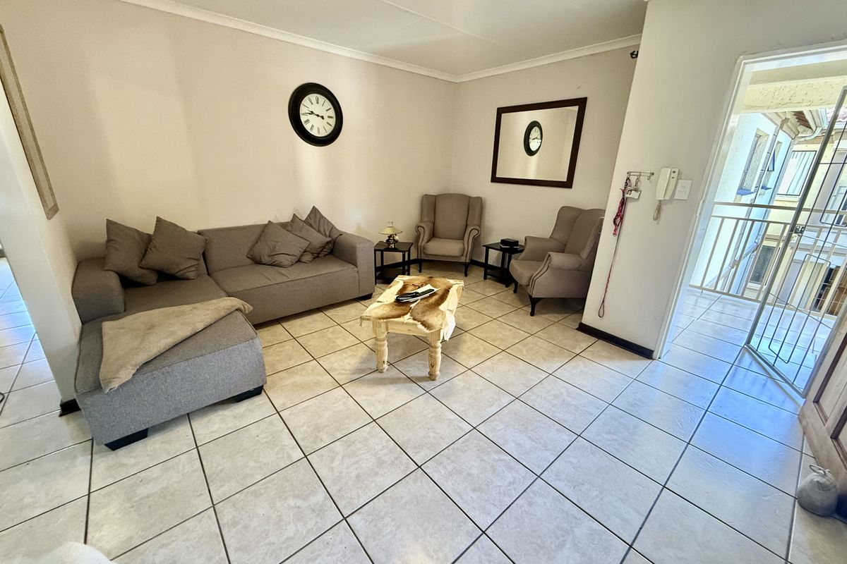 A well-lit living room featuring neutral tiled flooring and direct access to an outdoor balcony area.