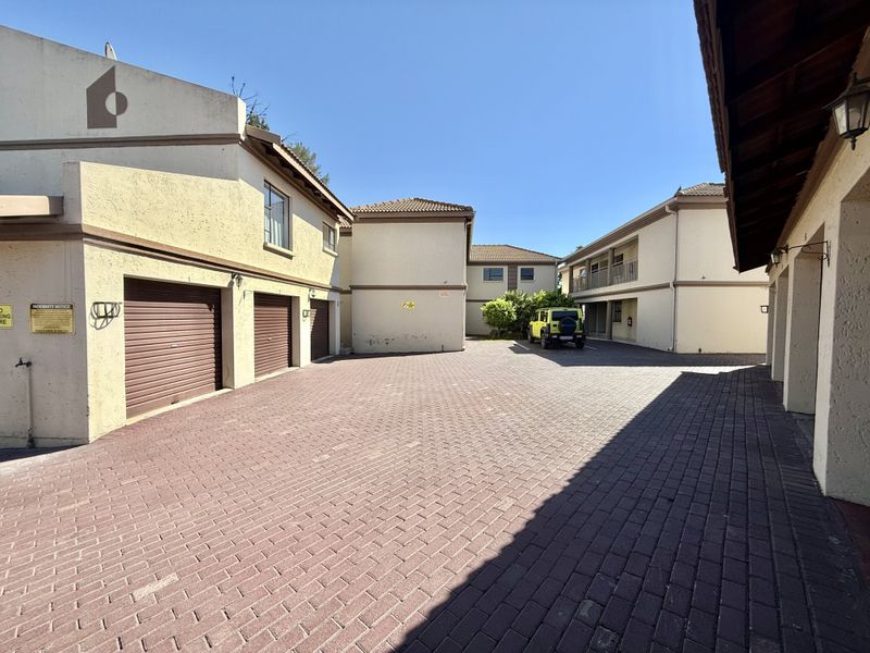 A paved courtyard area featuring multiple garage doors and access to the apartment complex buildings.