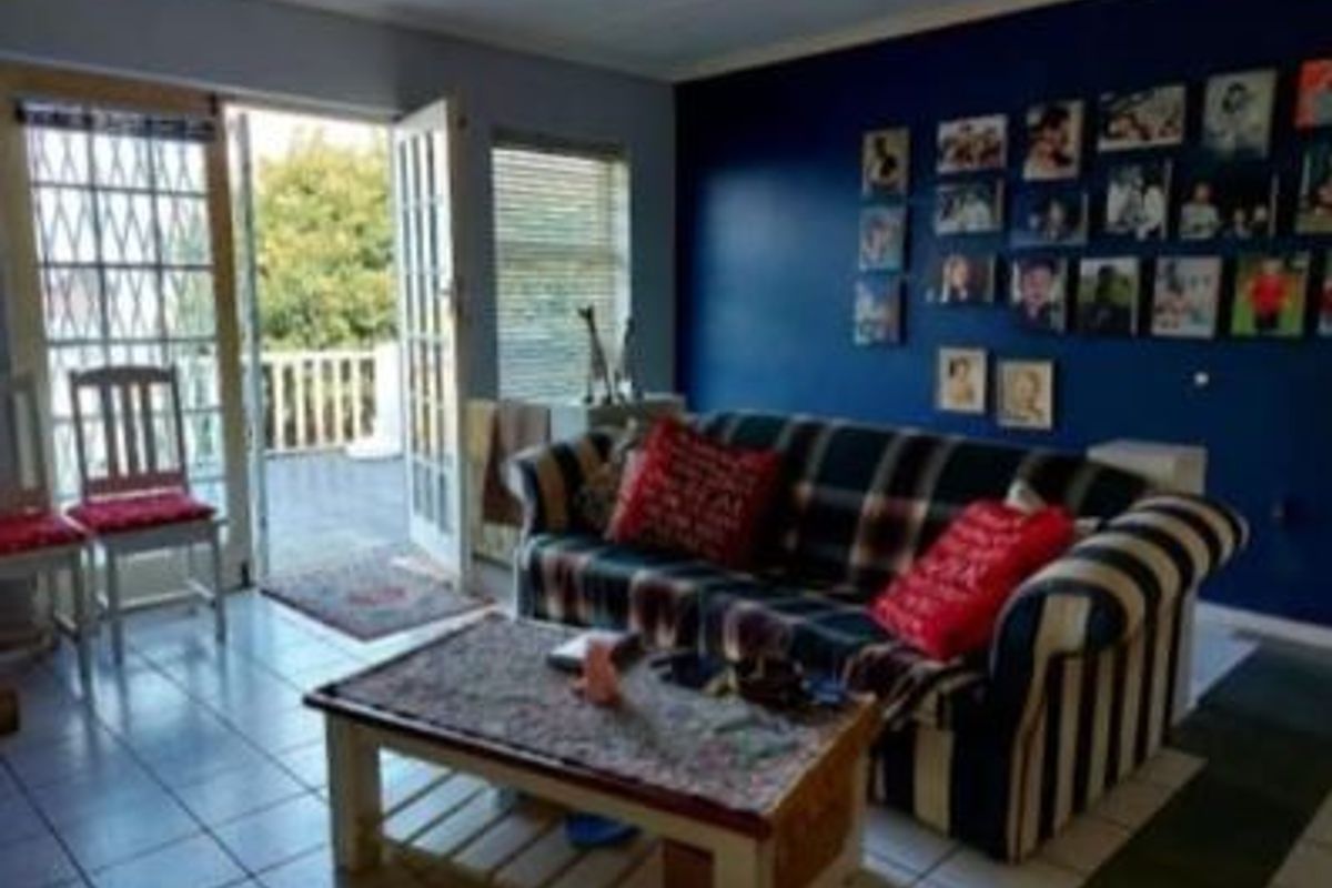 Living room featuring tiled flooring and direct access to an outdoor balcony through double french doors with security gate.