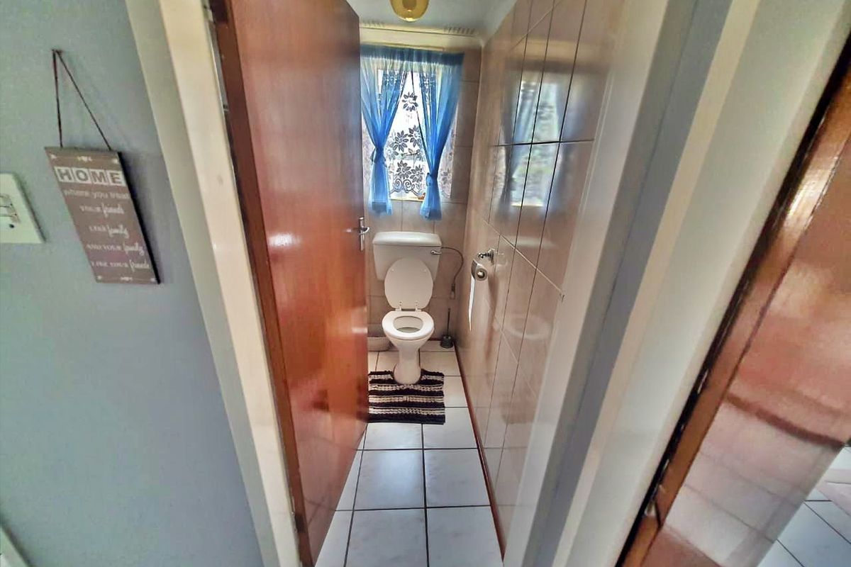 A compact bathroom featuring a standard toilet, tiled walls, and tiled flooring, presenting a dated aesthetic suitable for modernization.