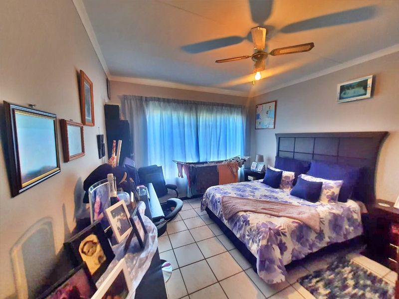A bedroom featuring tiled flooring and a ceiling fan, offering a functional space with natural light from the window.
