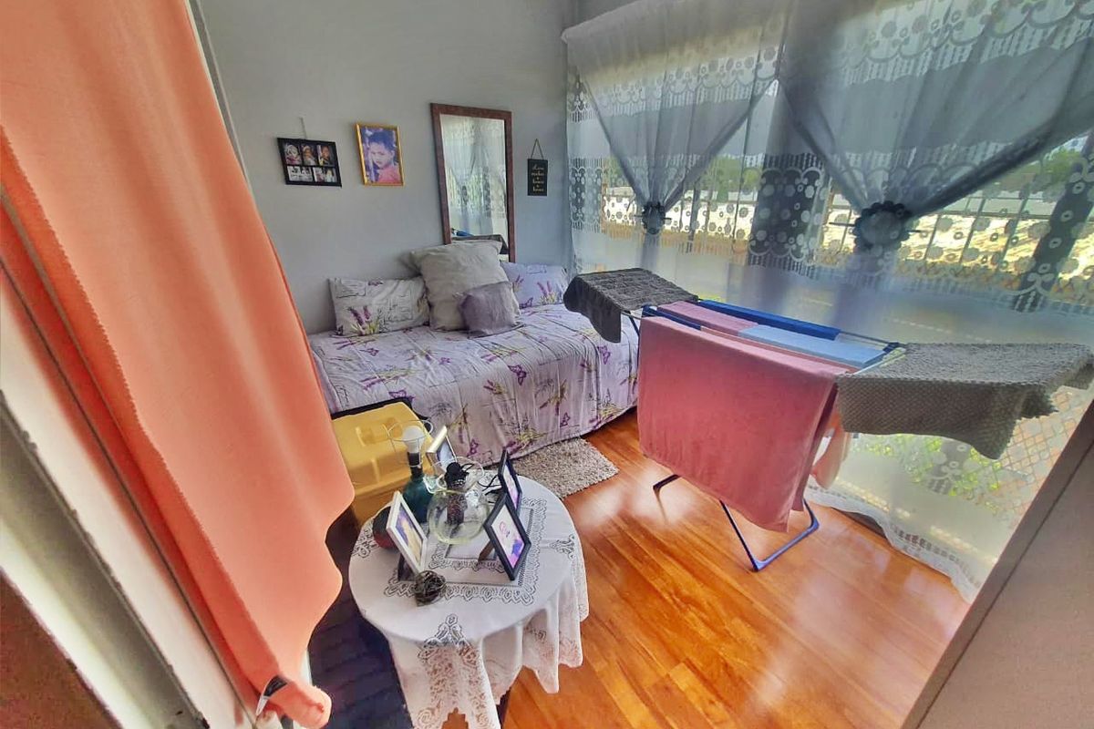 A bedroom featuring laminate flooring and a large window, providing natural light to the space.