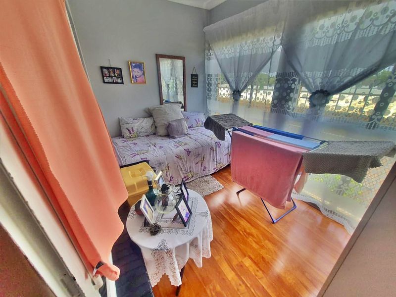 A bedroom featuring laminate flooring and a large window, providing natural light to the space.