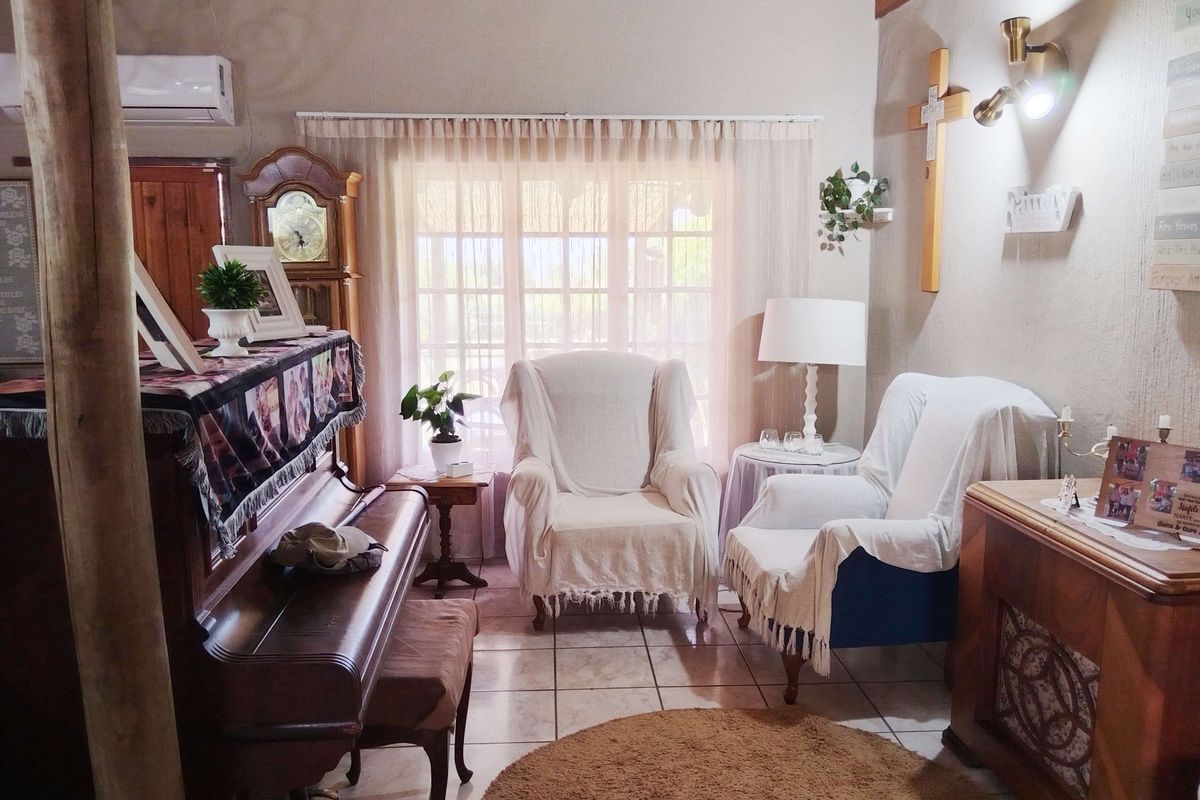 A cozy living room featuring tiled flooring, exposed timber ceiling beams, and a wall-mounted air conditioning unit.