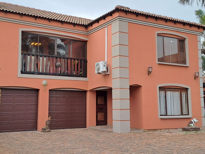 Front elevation of a two-story house featuring a double garage, upper-level balcony, and paved driveway access.