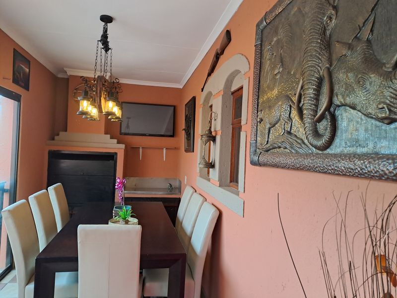 Covered patio area featuring a built-in fireplace, prep station with sink, and decorative lighting, suitable for outdoor dining and entertainment.