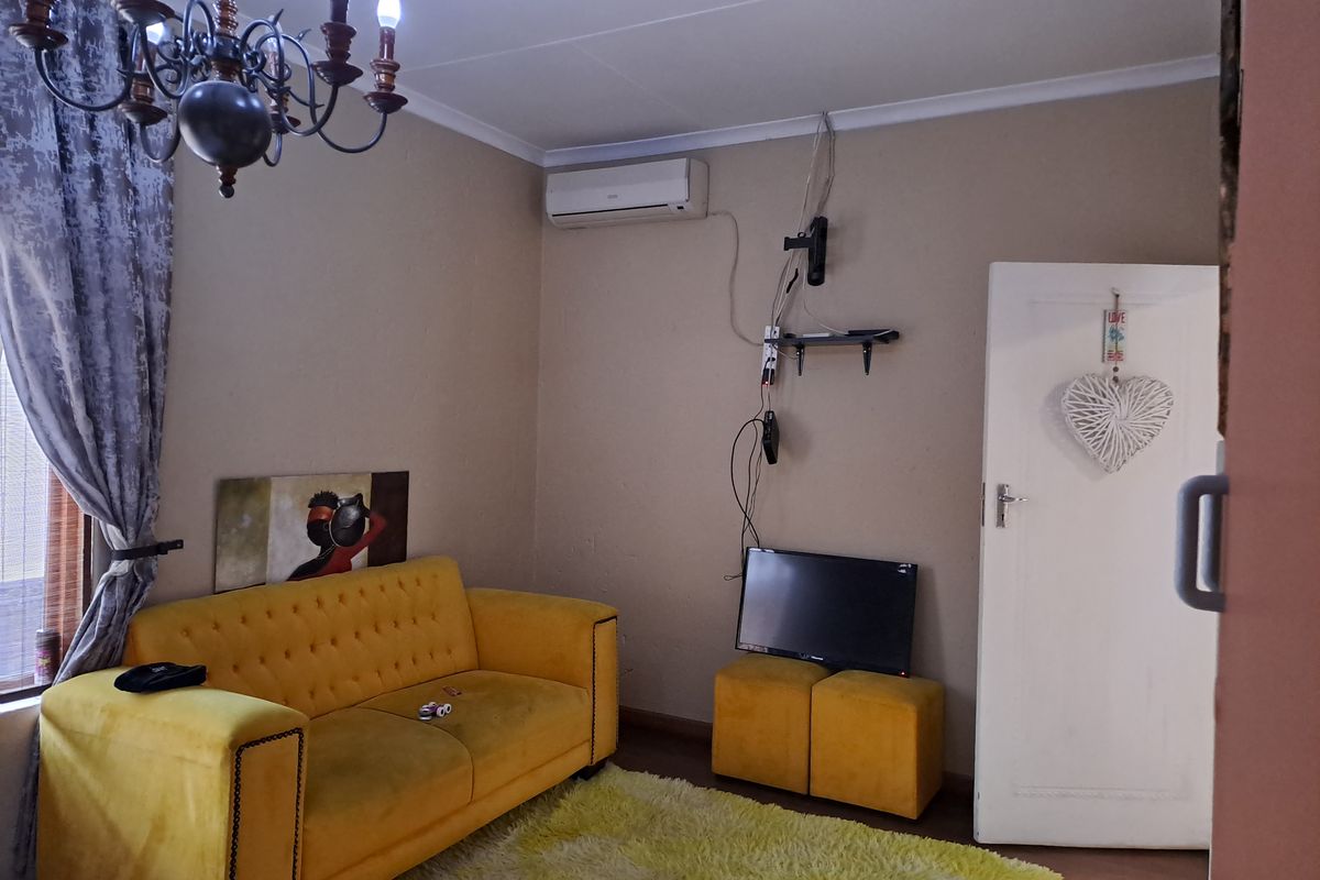 A living room featuring an air conditioning unit, coving, and a standard internal door, with visible wall scuffs and exposed wiring.