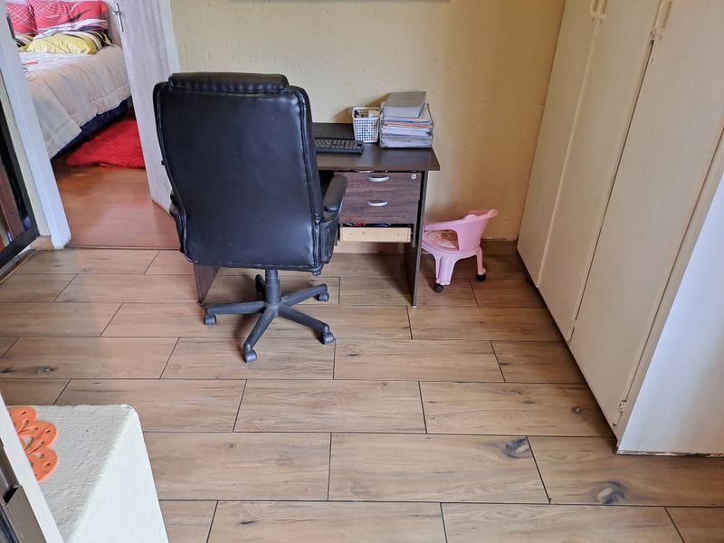 A functional office space featuring wood-look tile flooring and built-in storage cupboards, offering a practical area for work or study.