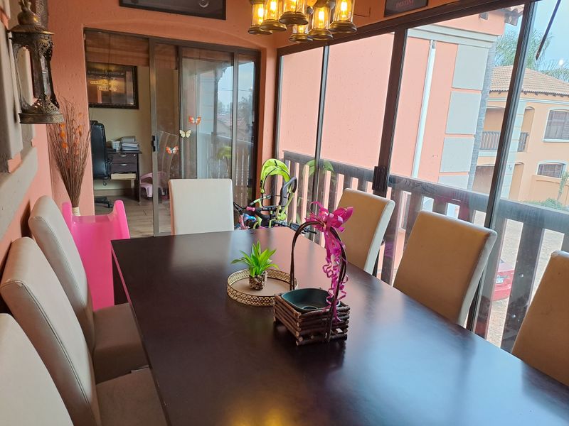 Enclosed balcony or patio area featuring large sliding glass doors, a wooden railing, and overhead pendant lighting, suitable for dining or relaxation.