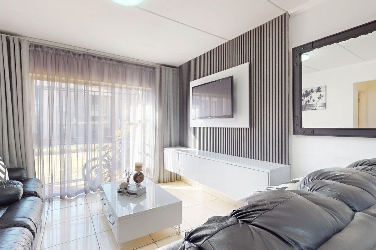Modern living room featuring a stylish slatted feature wall, built-in media console, and bright tiled flooring with large windows allowing natural light.