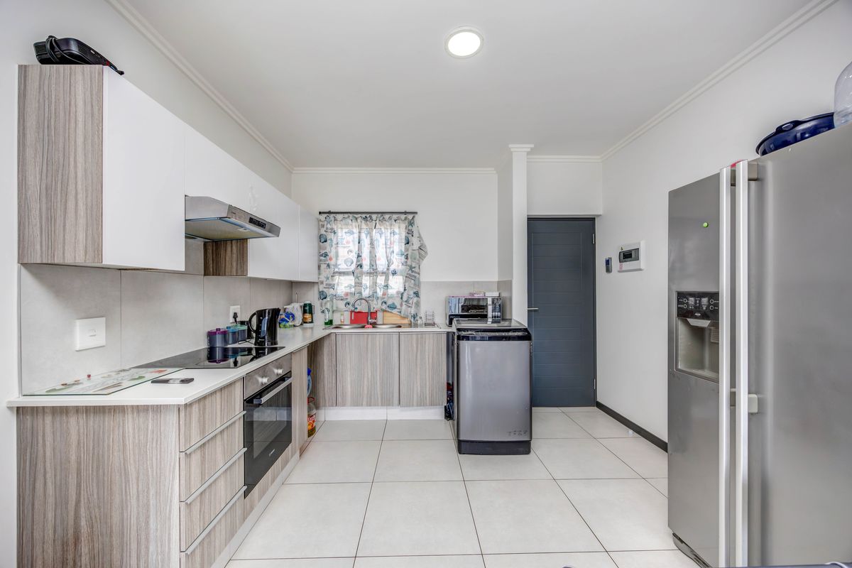 Modern kitchen featuring light wood-grain cabinetry, white countertops, integrated appliances, and tiled flooring, offering a clean and functional workspace.