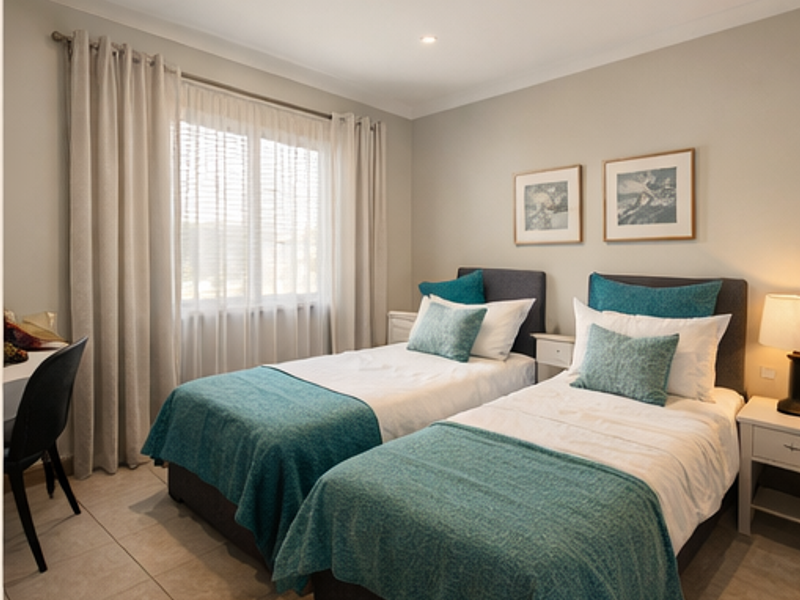 A well-maintained bedroom featuring neutral wall tones, tiled flooring, and recessed downlighting, offering a clean and comfortable living space.