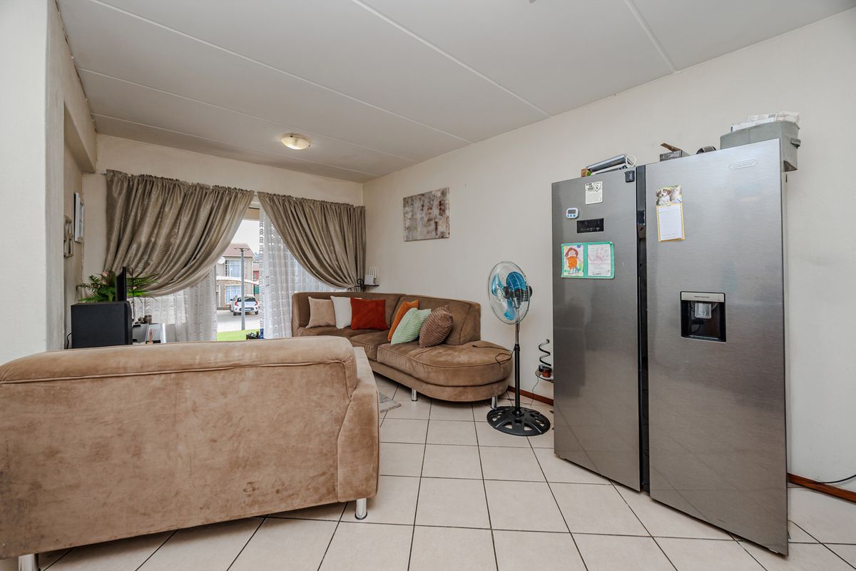 A living room area featuring tiled flooring and a sliding glass door providing access to the exterior.