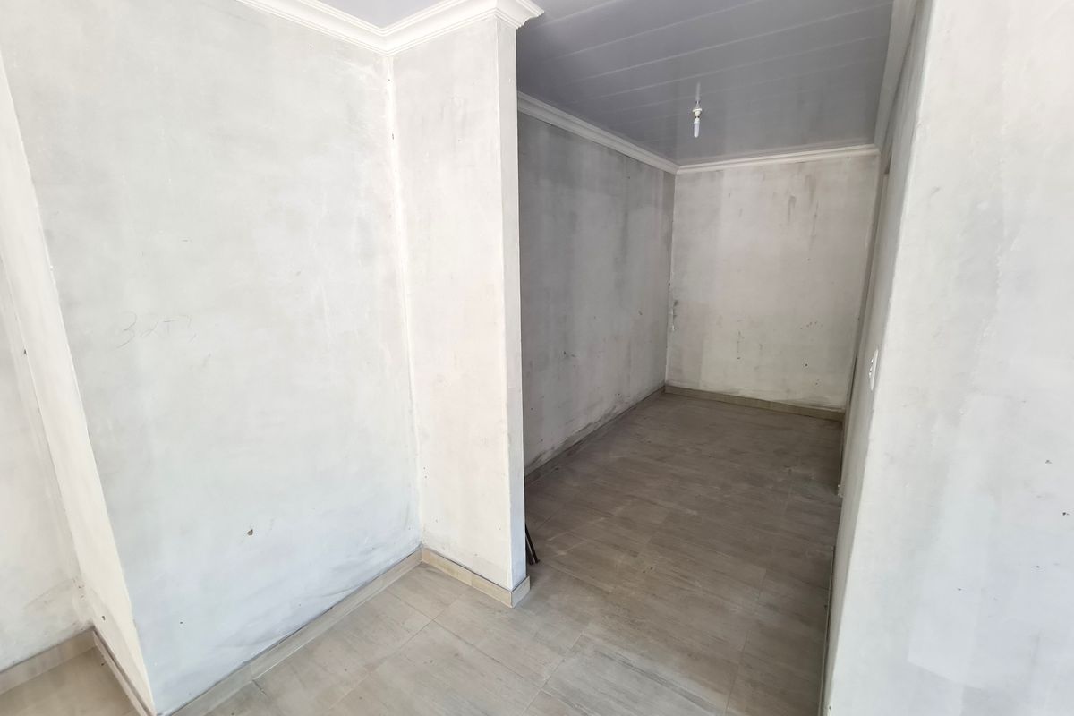 An empty, unfinished room featuring tiled flooring and coved ceilings, presenting a blank canvas ready for final wall finishes and interior design.