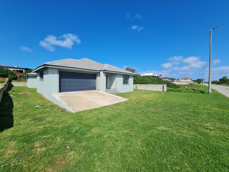 A modern single-story house featuring a tiled roof, a concrete driveway, and an integrated garage, situated on a spacious corner plot.