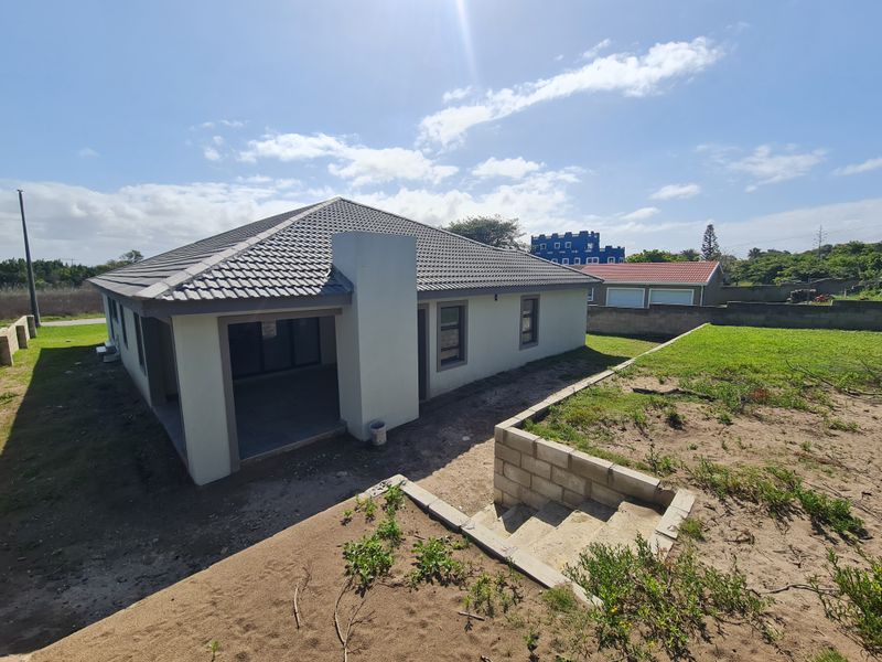 Rear view of the property featuring a covered patio, tiled roof, and unfinished garden area with concrete retaining walls and stairs.
