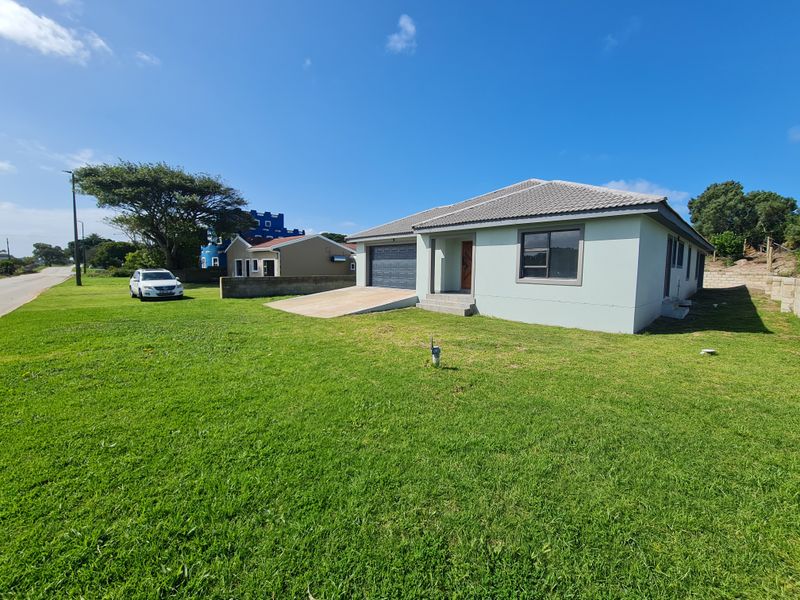 Front view of a single-story residential house featuring a tiled roof, concrete driveway, and attached garage on a spacious grass lot.